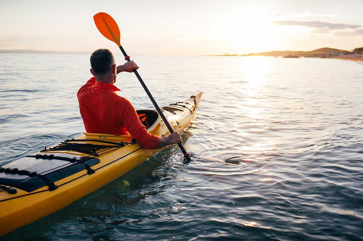 Kayaker on water facing sunrise